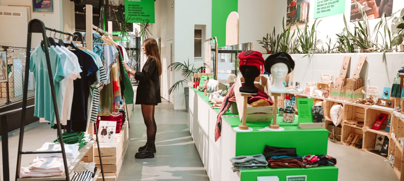 Une cliente explore le magasin hors cadre de l'Office de Tourisme à Saint-Étienne, dotée de vêtements, accessoires et objets design.